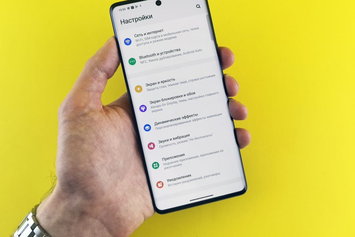 A hand holding a smartphone open at its network settings menu against a yellow background