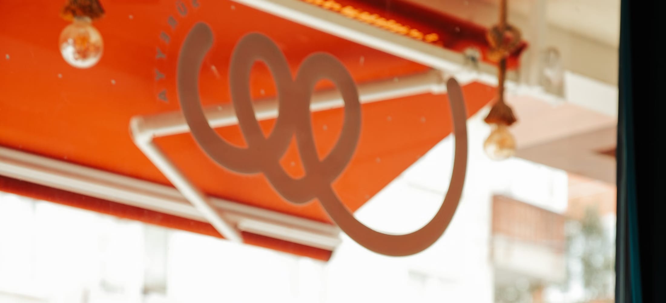Curved orange ceiling lighting and hanging pendant lamps in a warmly lit café interior