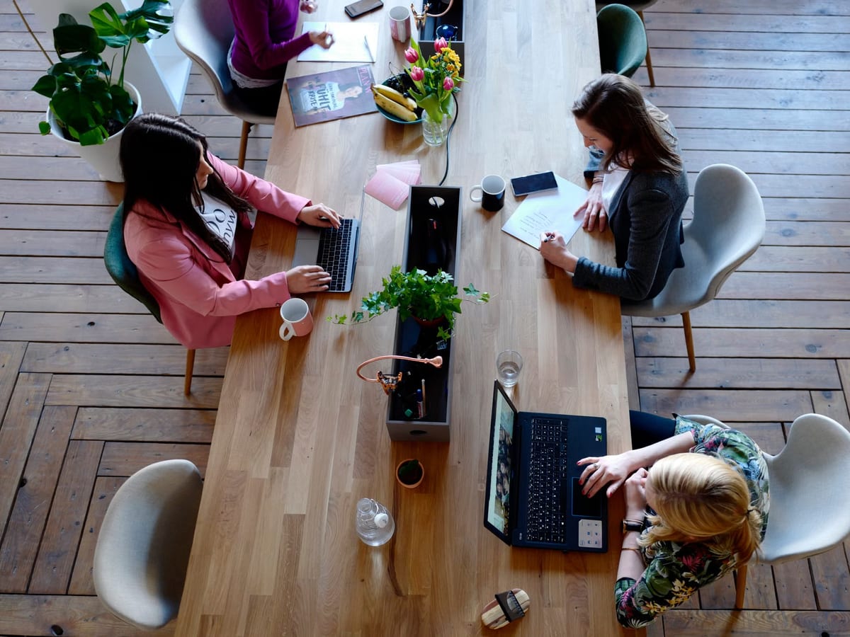 Colleagues working on laptops around a long shared table, photographed from above